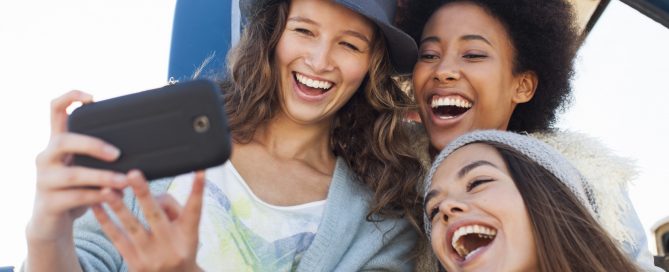 Friends taking photo with mobile phone by truck